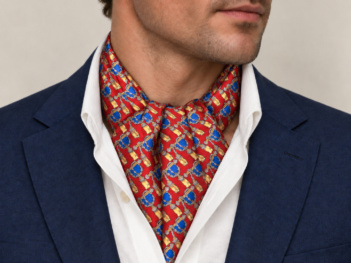 Neven Heritage red silk ascot tie with blue and gold ornamental motifs worn with a navy jacket