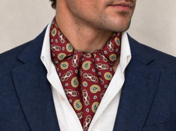 Burgundy silk ascot with gold paisley and equestrian motifs worn under a white shirt with a navy jacket