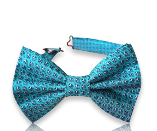 Neven turquoise silk twill bow tie with small navy abstract motifs and an adjustable neck strap on a white background.